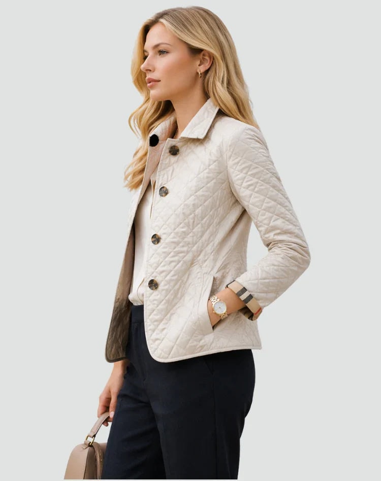 Side view of an ivory diamond-quilted button-front jacket showing its structured shirt collar, long sleeve, rounded hem, and side pocket.