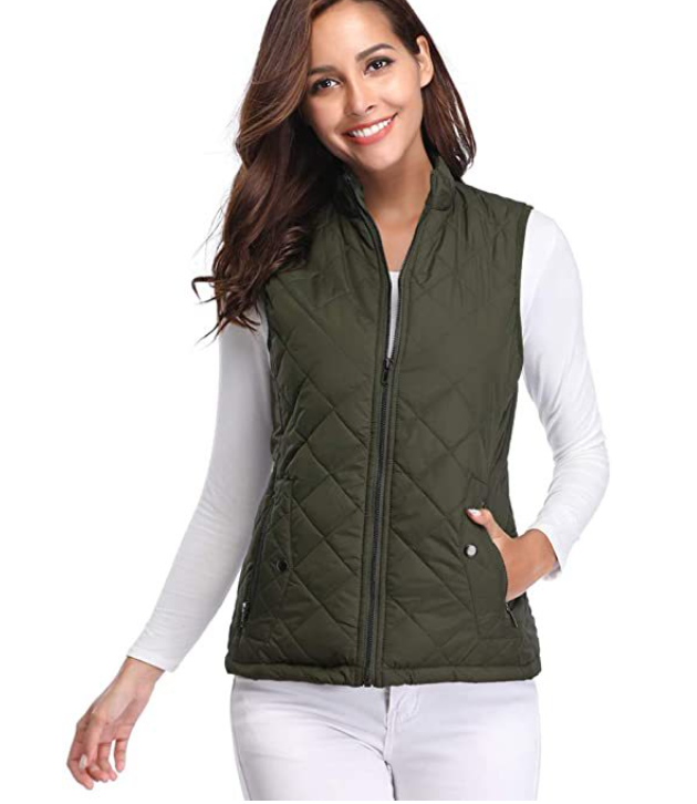 Olive green quilted vest modeled with one hand in a pocket, showing its sleeveless shape and hip-length fit.