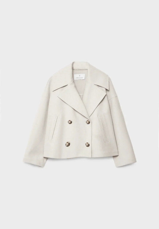 Front view of a cream cropped jacket with wide notched lapels, four buttons, long sleeves, and slanted front pockets.
