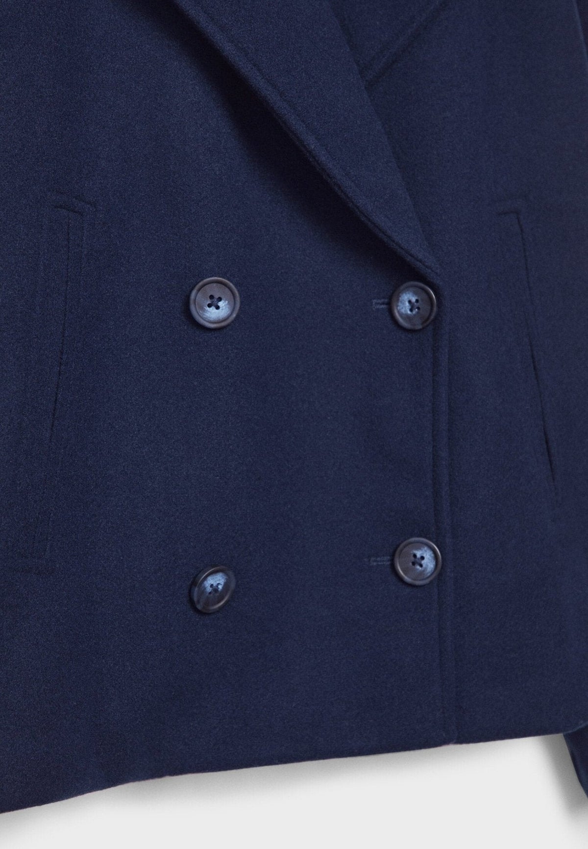 Close-up of the navy jacket showing four buttons, the notched lapel edge, and a vertical pocket opening.
