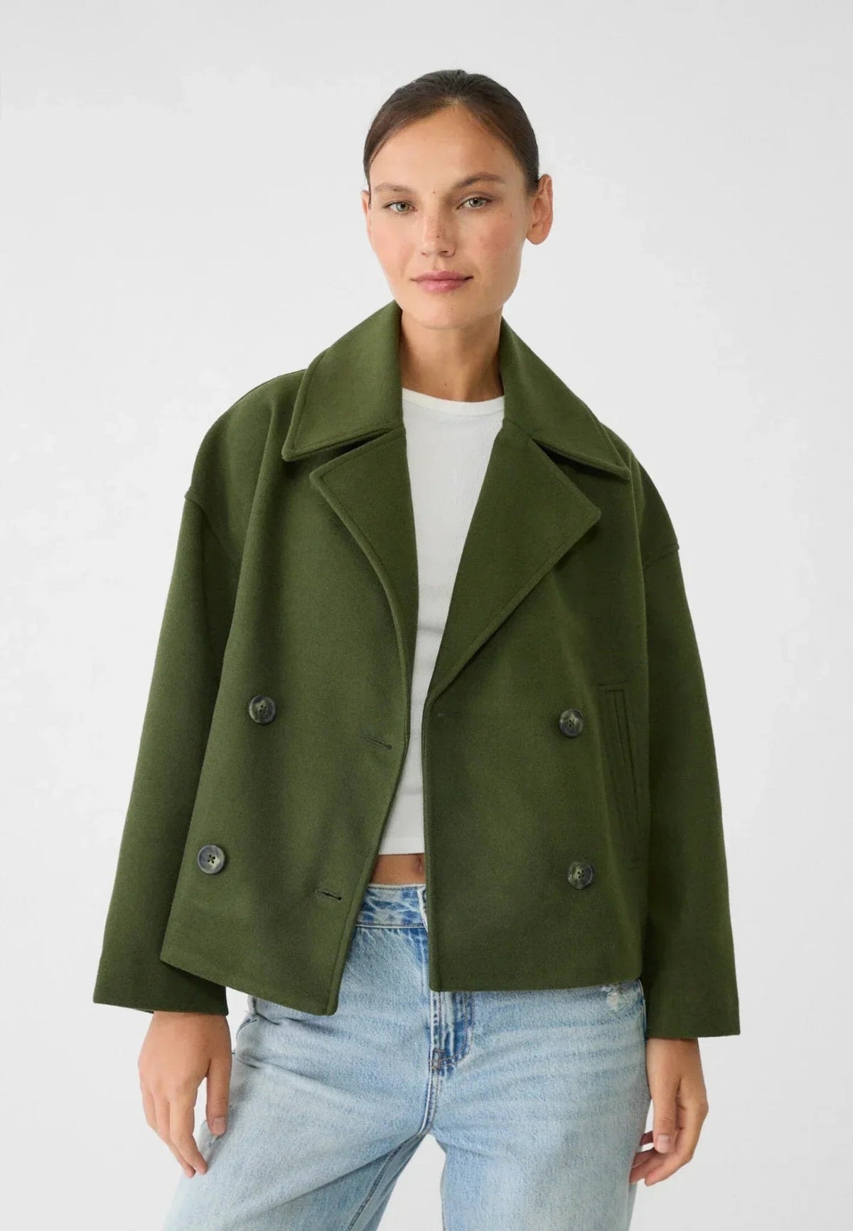 Model wearing the olive green cropped jacket with a white top and light blue jeans, showing the structured lapels and long sleeves.