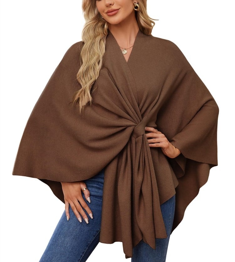 Brown poncho wrap with deep front folds gathered into a tie over blue jeans.