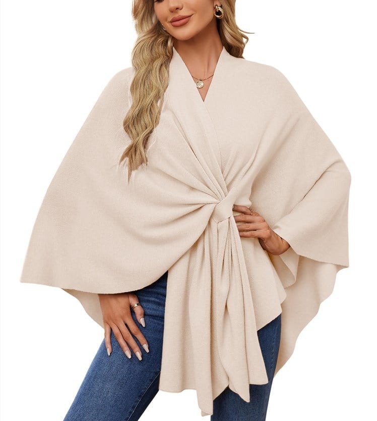 Light cream poncho wrap featuring a soft gathered center and wide, flowing sleeves.
