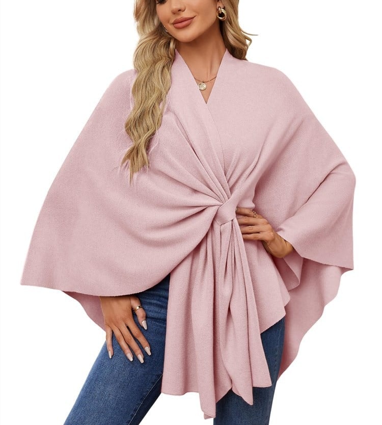 Soft pink poncho wrap with wide sleeves and a gathered tie-front detail cascading downward.