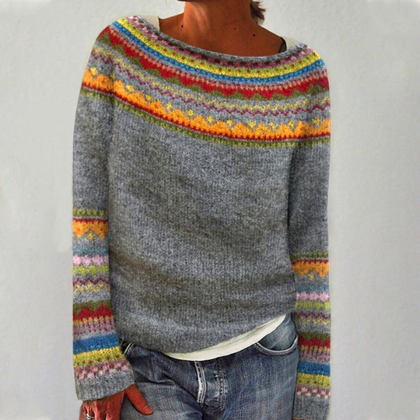 Gray Fair Isle crew neck sweater featuring colorful patterned bands around the neckline and cuffs, worn with jeans.