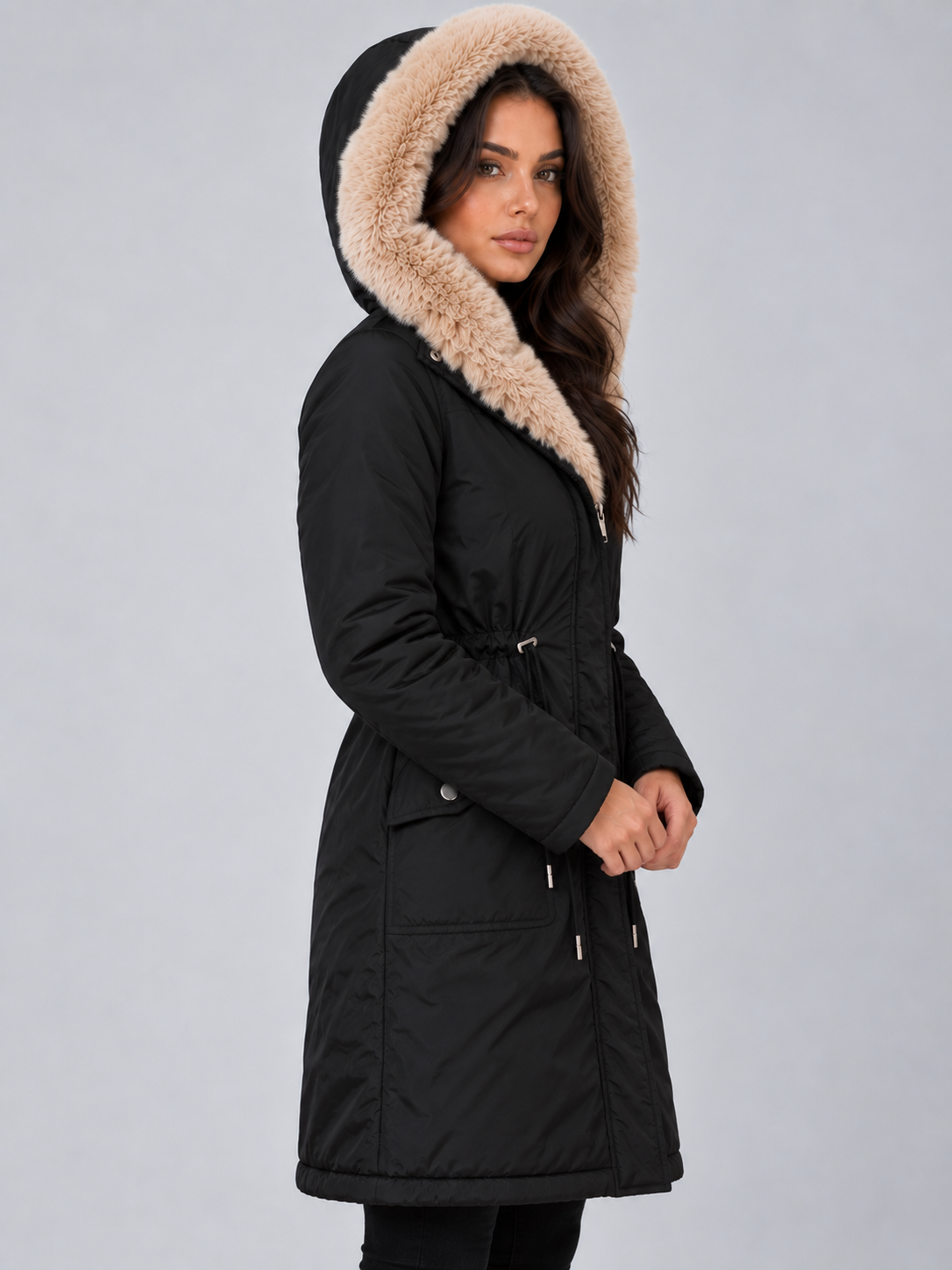 Side view of the black hooded parka with the hood raised, showing its long silhouette, waist adjustment, and pocket flap.