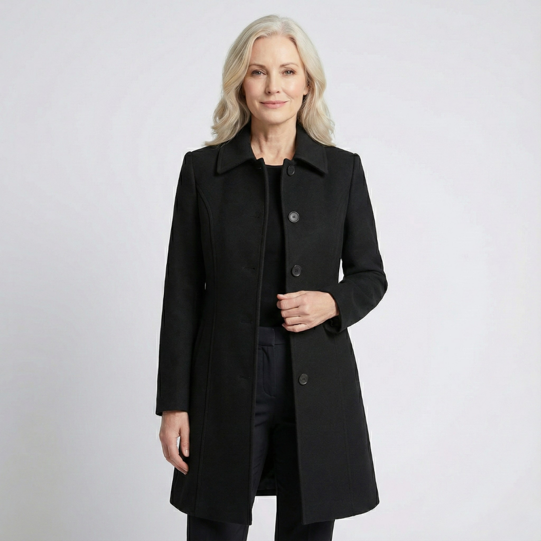 Black fit-and-flare coat with a pointed collar, button-front closure, long sleeves, and above-knee length, worn open.
