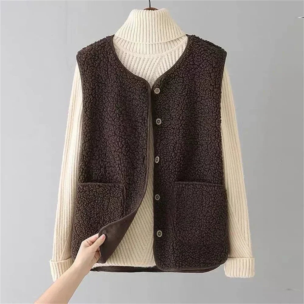 Dark brown fleece vest shown front-on over a light ribbed sweater, highlighting the button closure, V-neckline and two large patch pockets.