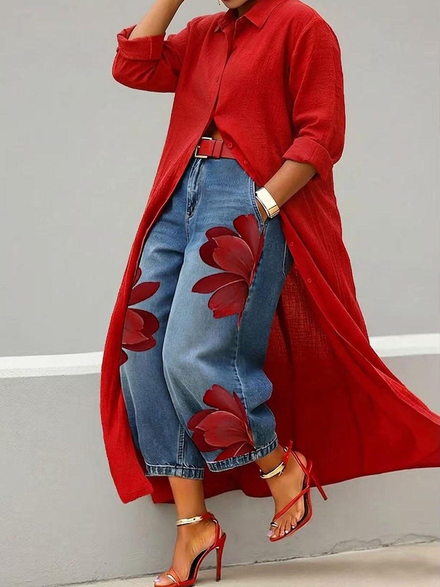 Cropped floral-print jeans shown in motion, with the wide-leg silhouette and ankle-length hems visible beneath a red longline shirt.