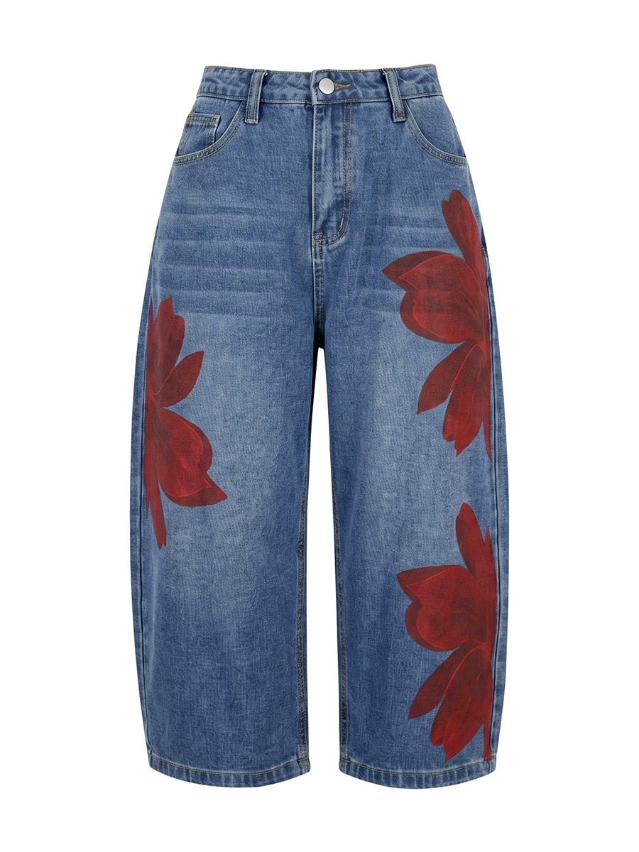 Full product view of blue cropped wide-leg jeans with four oversized red floral motifs, belt loops, front pockets, and a button closure.