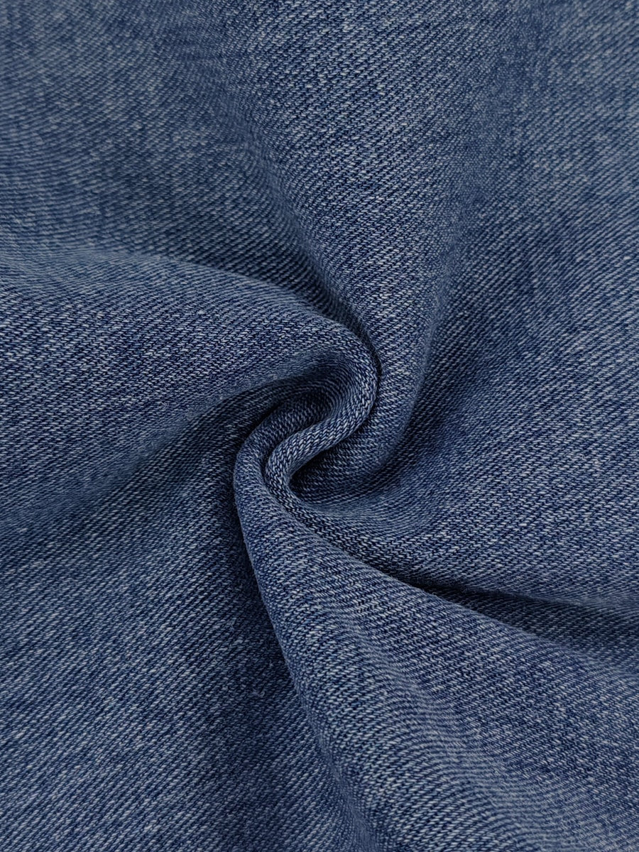 Close-up of the blue textile gathered into a spiral fold, emphasizing the fabric’s fine woven surface.