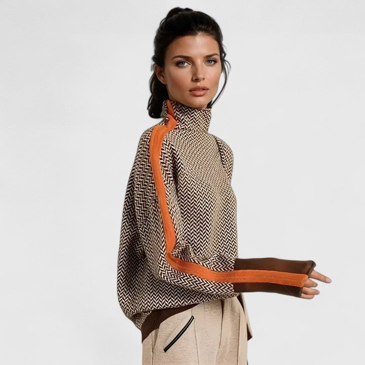 Model wearing the high-neck sweater with a repeating herringbone pattern and orange-and-brown contrast stripes along the sleeves.