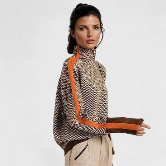Model wearing the high-neck sweater with a repeating herringbone pattern and orange-and-brown contrast stripes along the sleeves.
