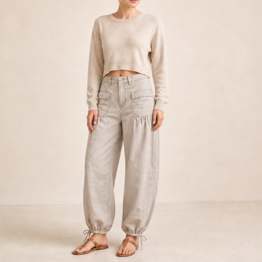 Front view of the jeans design in a light cream color with cargo pockets, curved legs, and tied ankle hems.