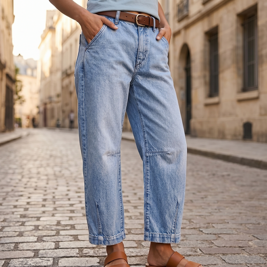 Close view of light-blue high-waisted cropped barrel-leg jeans showing the curved relaxed legs, knee seam detailing, pockets, and sandals at the hem.