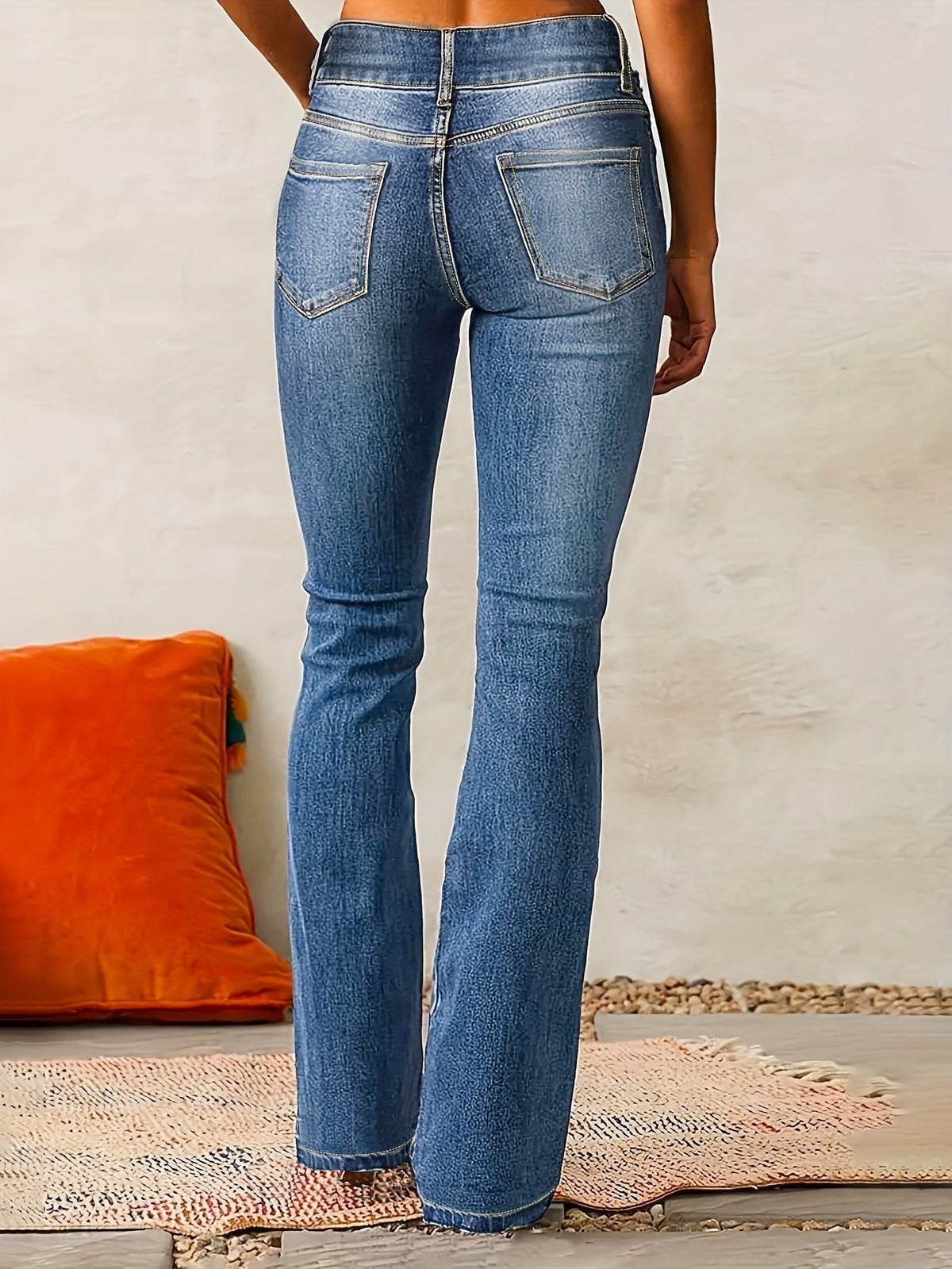 Back view of blue high-waisted flared jeans showing the two rear patch pockets and flared full-length legs.