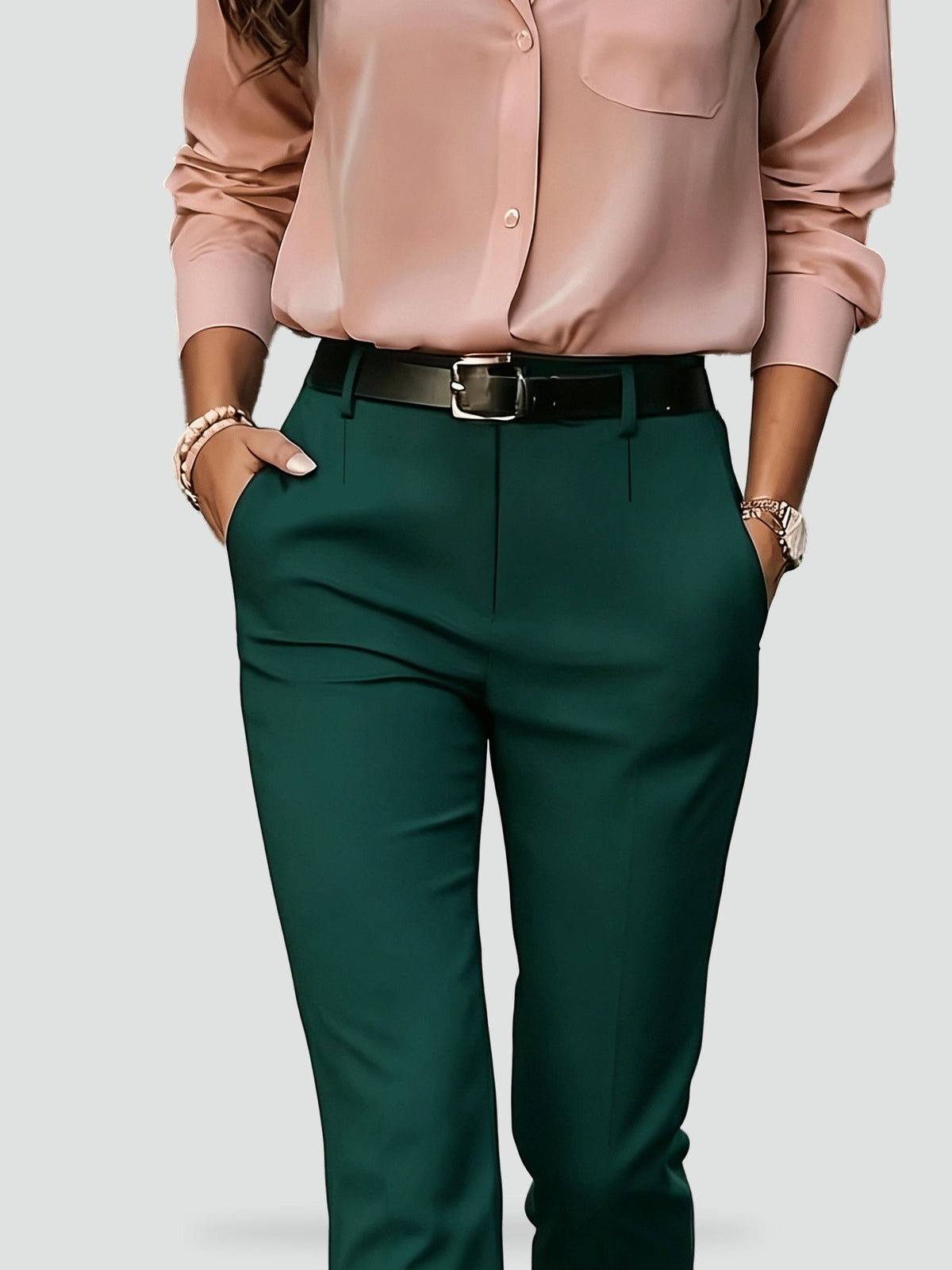 Close-up of green high-waisted trousers highlighting the waistband, front closure, belt loops, and angled pocket openings.