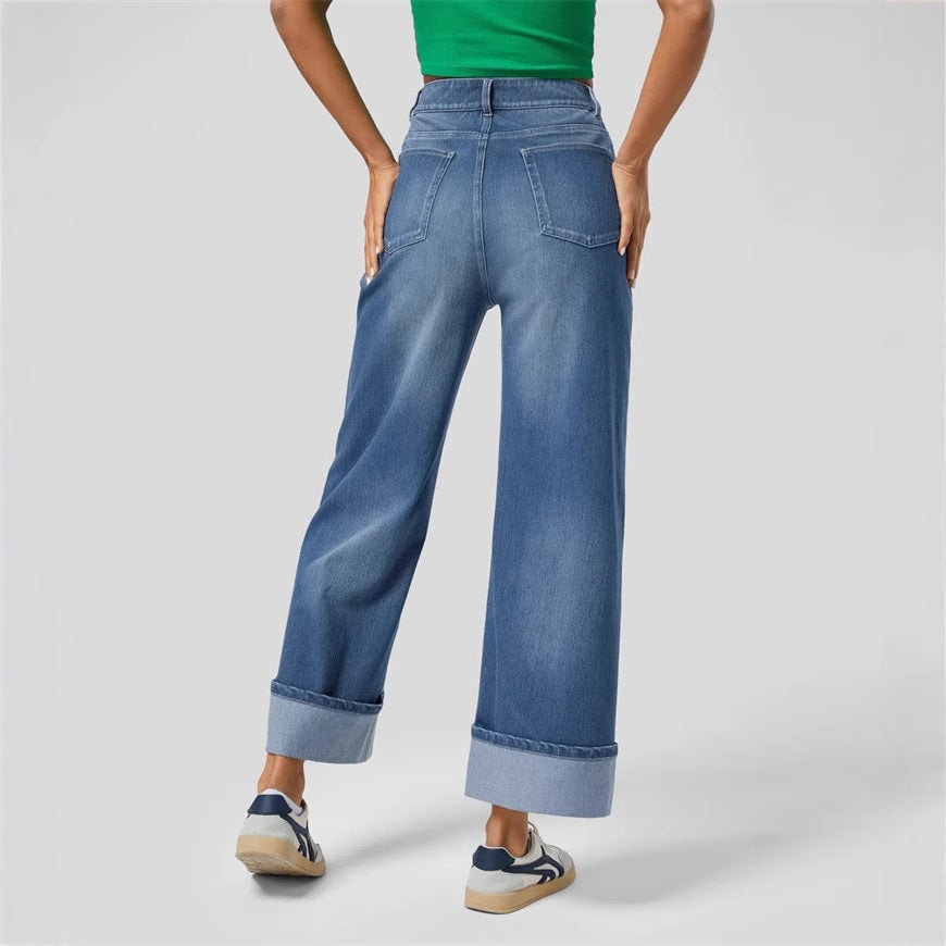 Back view of the blue jeans highlighting the rear waistband, patch pockets, wide legs, and large cuffed hems.