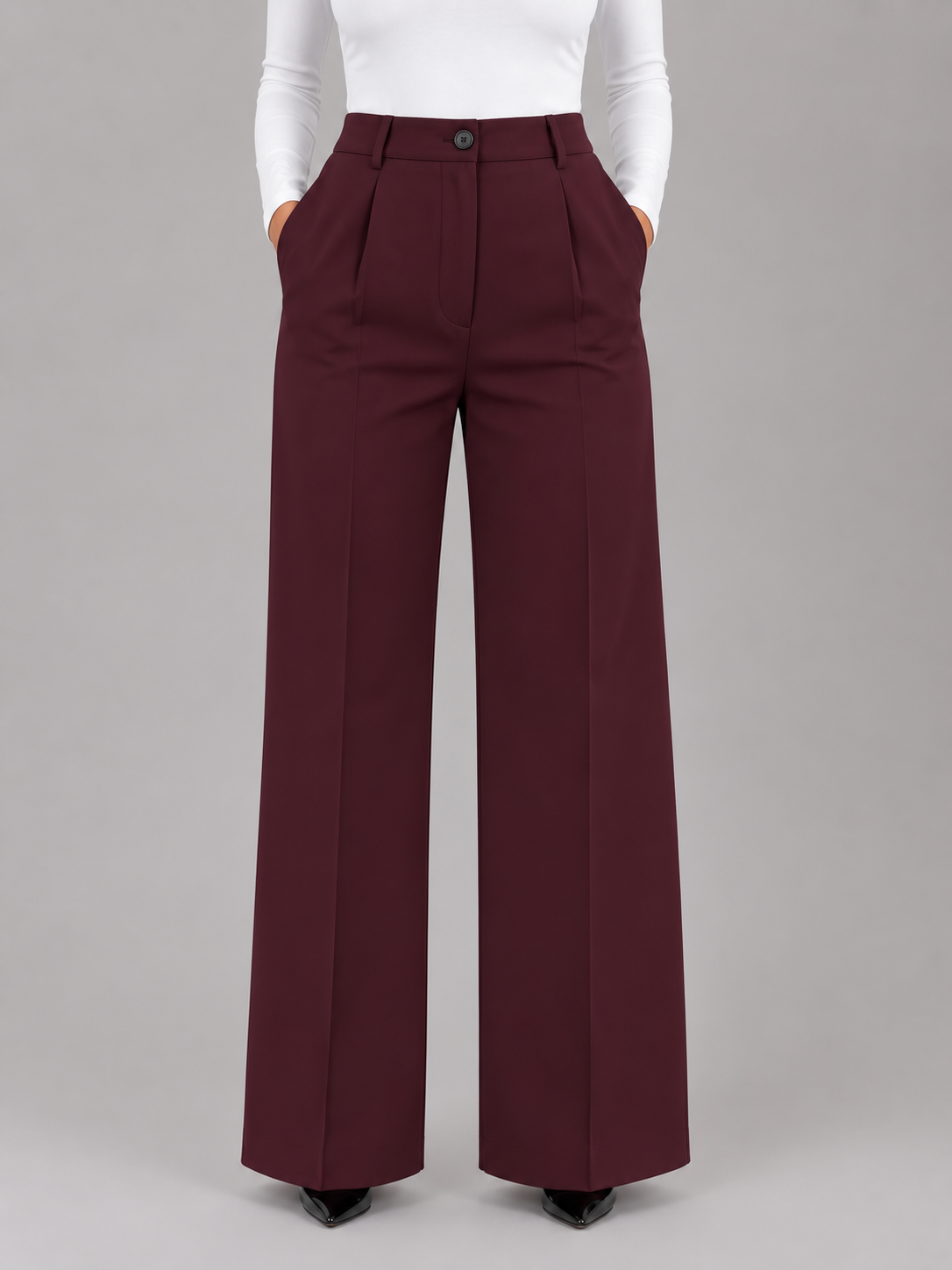 Front view of burgundy high-waisted wide-leg trousers with defined pleats, a button closure, and side pockets.