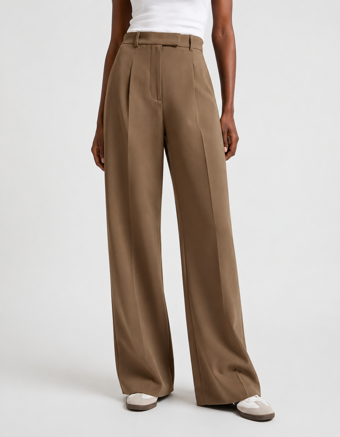 Front view of brown high-waisted trousers with structured pleats and flowing wide legs.
