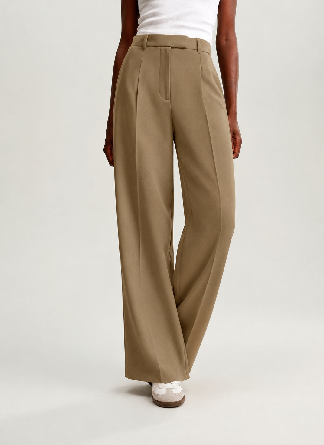 Front view of tan high-waisted trousers with crossed legs emphasizing the wide-leg silhouette and full-length cut.