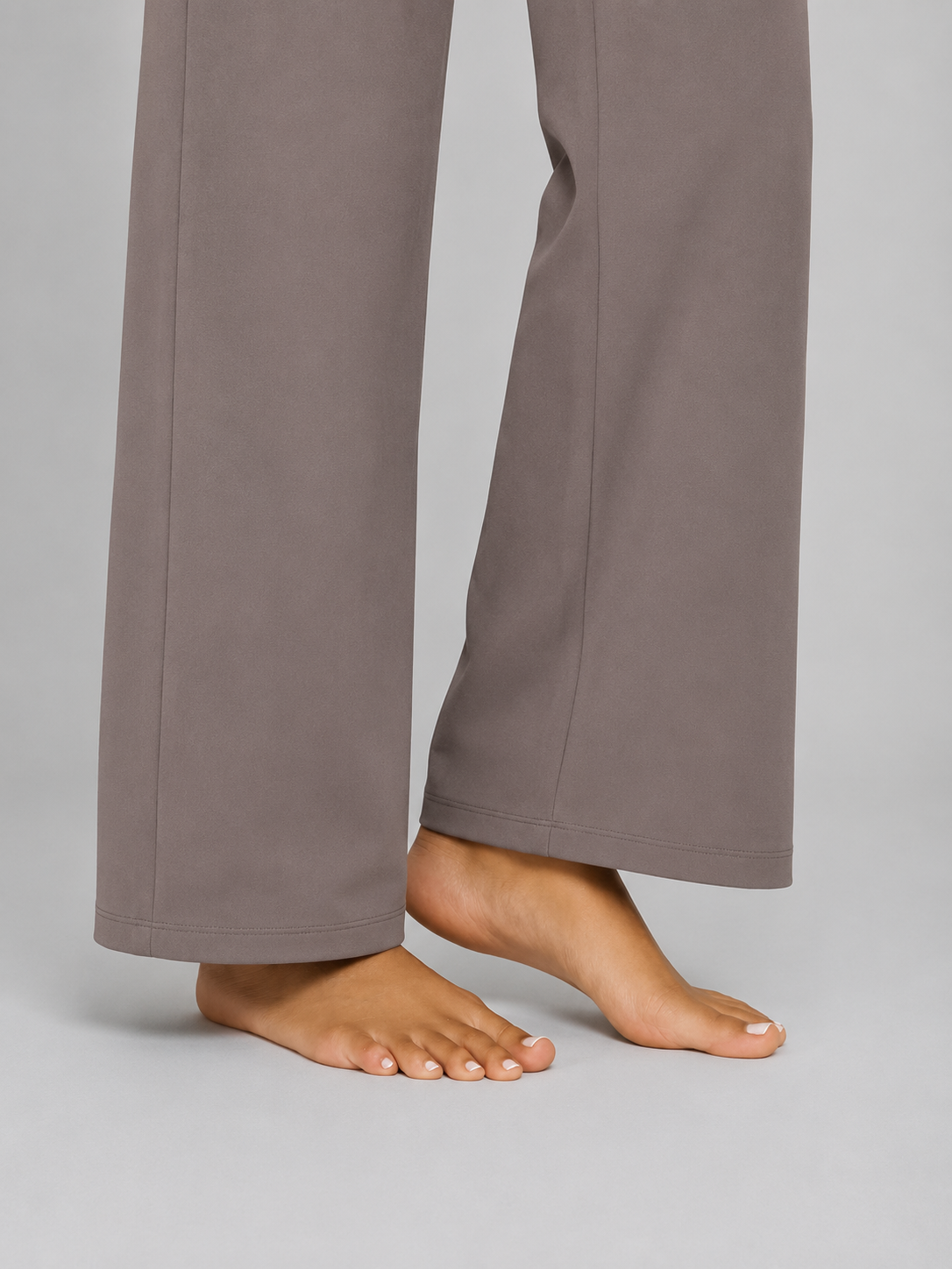Close view of the full-length wide-leg hems and clean stitching on taupe trousers.