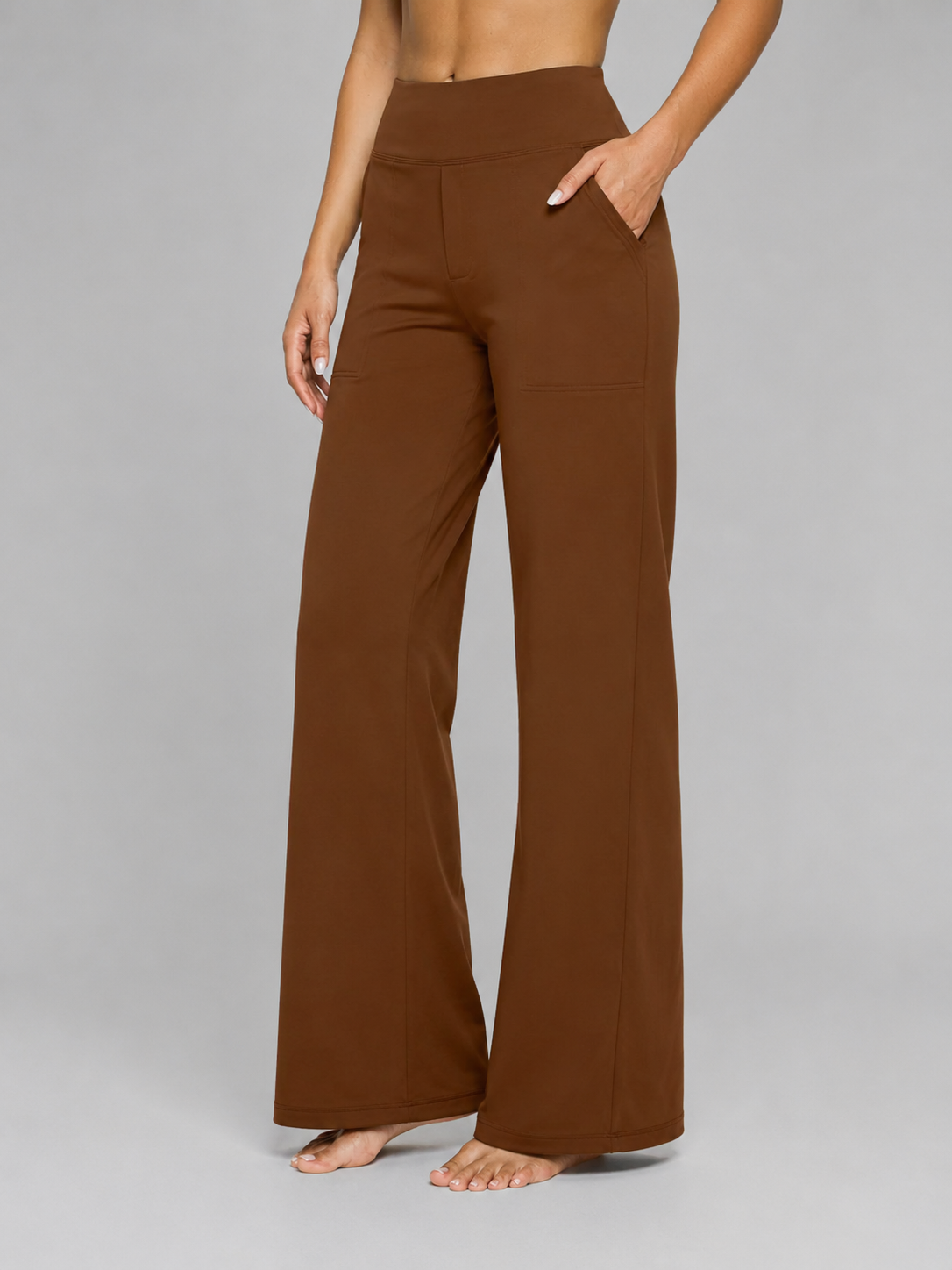 Front view of the wide-leg trousers in deep brown, with a high waist and hand in the side pocket.