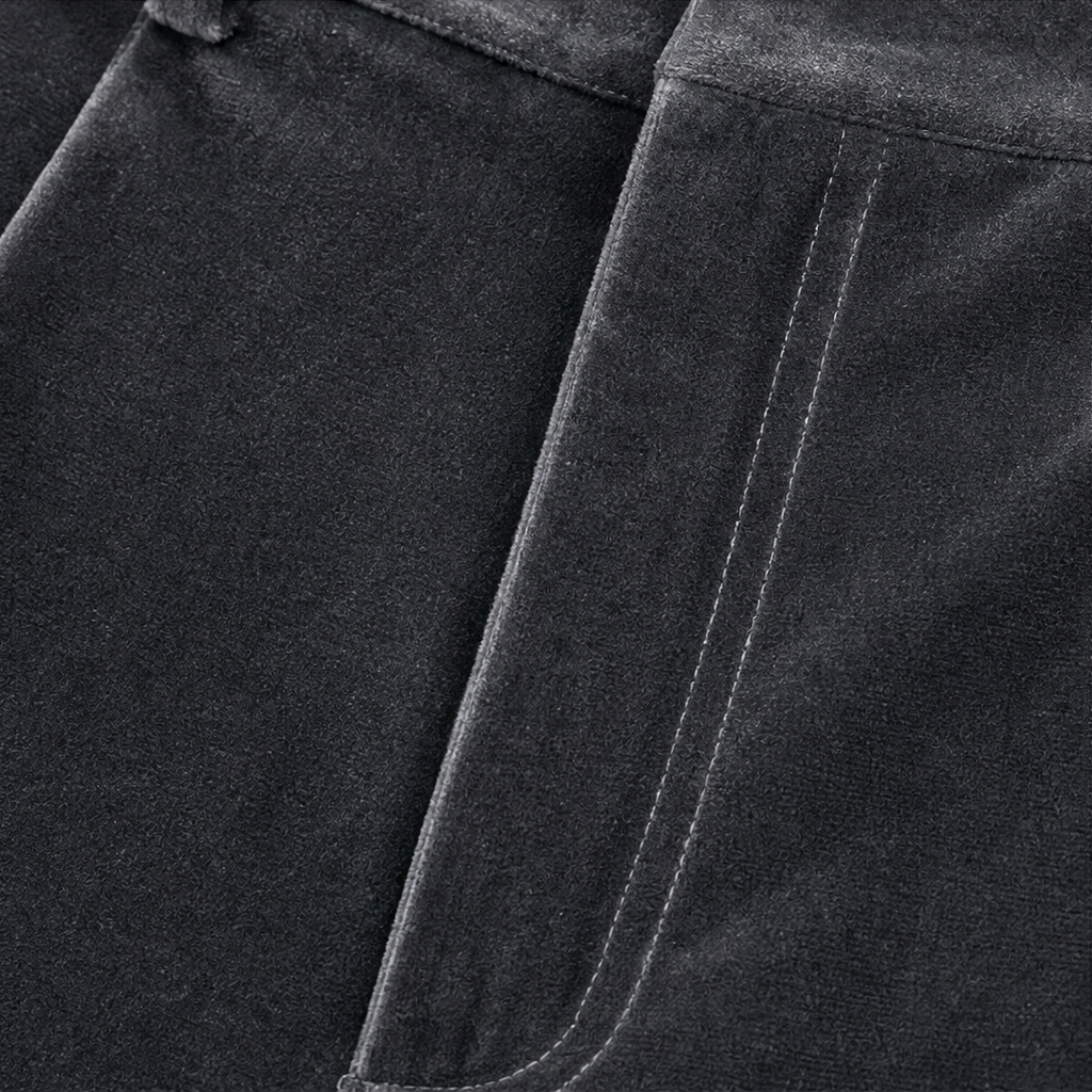 Detailed view of the curved opening and stitching of a side pocket on the dark trousers.