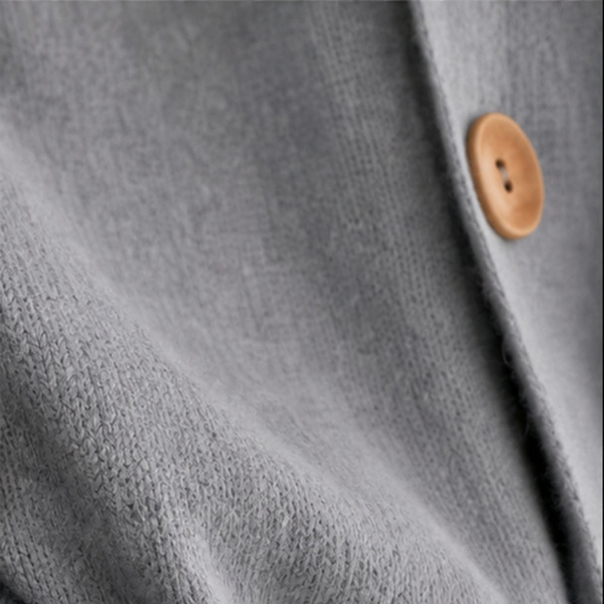 Close-up of the gray cardigan’s front edge with a partially visible wooden button.