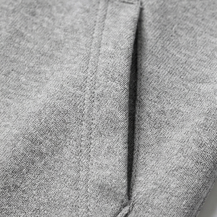 Close-up of a vertical stitched edge and opening along the gray cardigan.