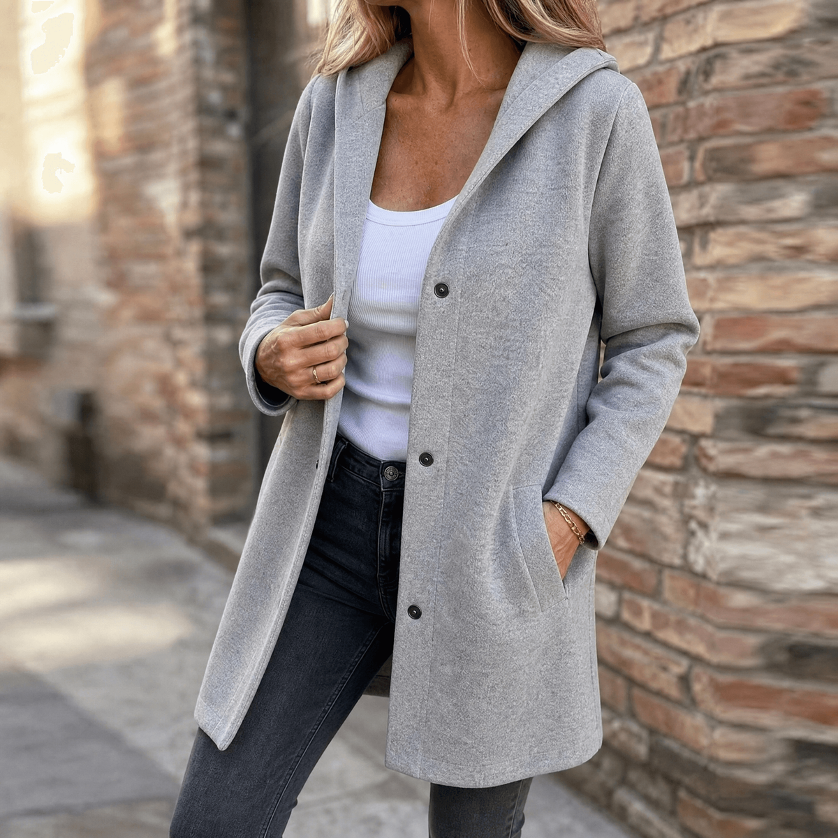 Gray hooded cardigan worn partly fastened, highlighting the front button closure and right patch pocket.