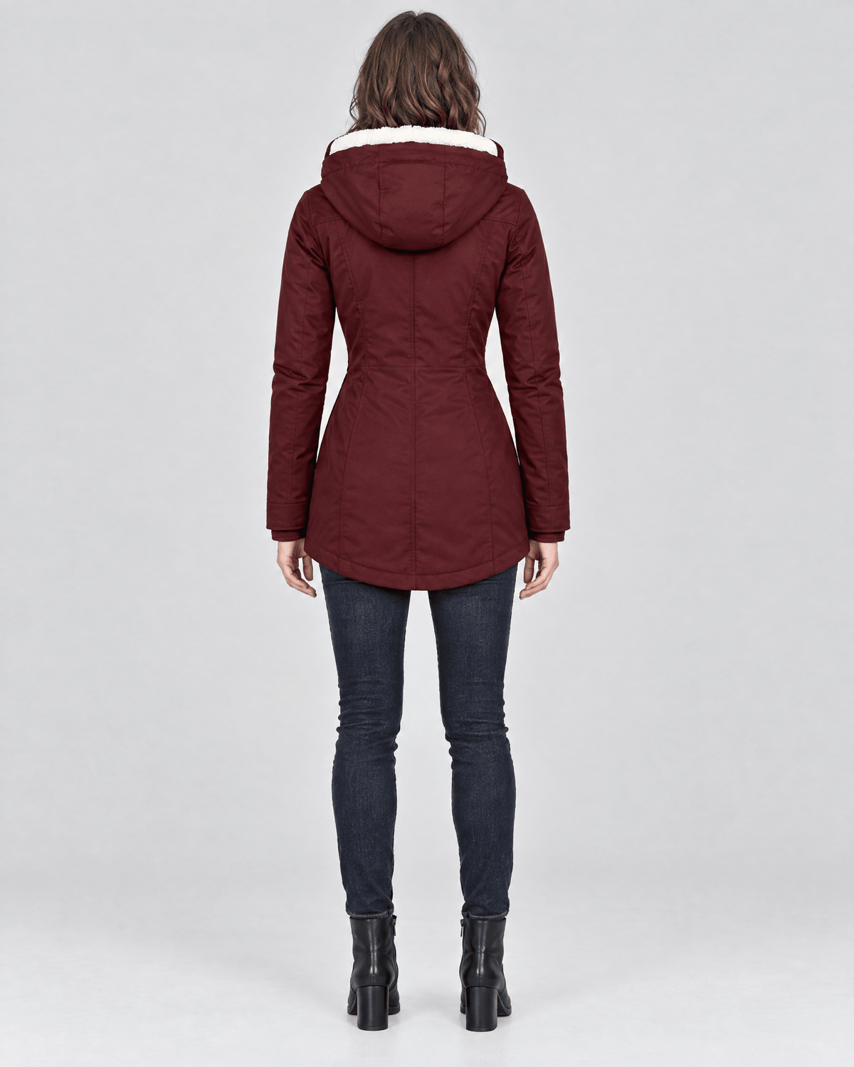 Back view of the burgundy jacket showing the attached hood, shaped waist, long sleeves, and curved mid-length hem.