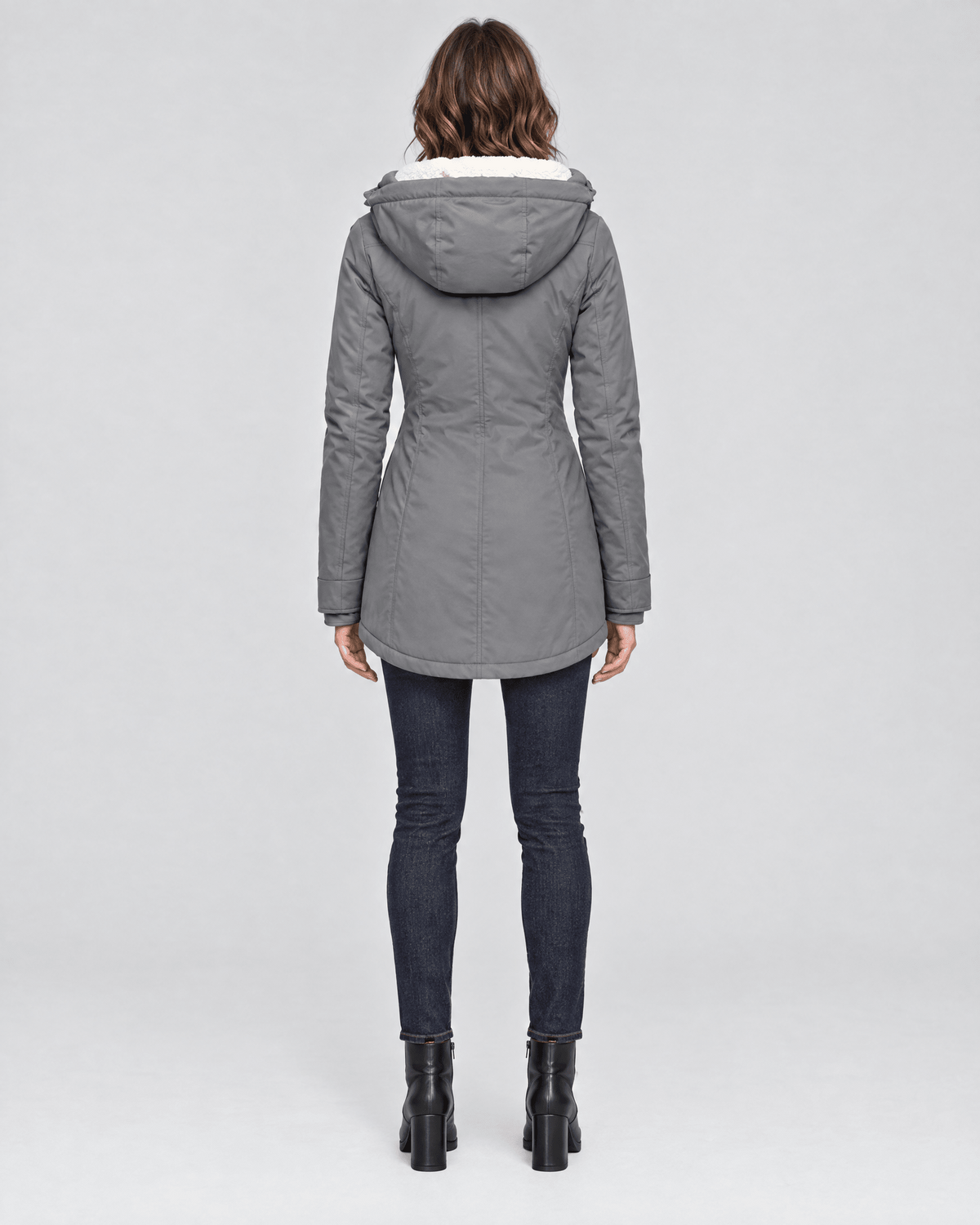 Back view of the gray winter jacket showing its adjustable hood, long sleeves, fitted waist, and curved mid-length hem.