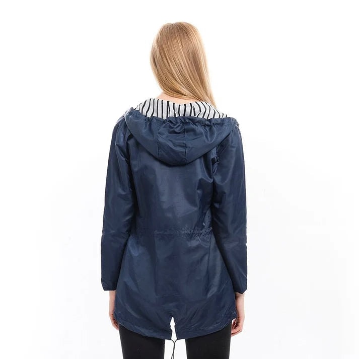 Back view of the navy raincoat showing its hood, long sleeves, adjustable waist, and mid-thigh-length hem.