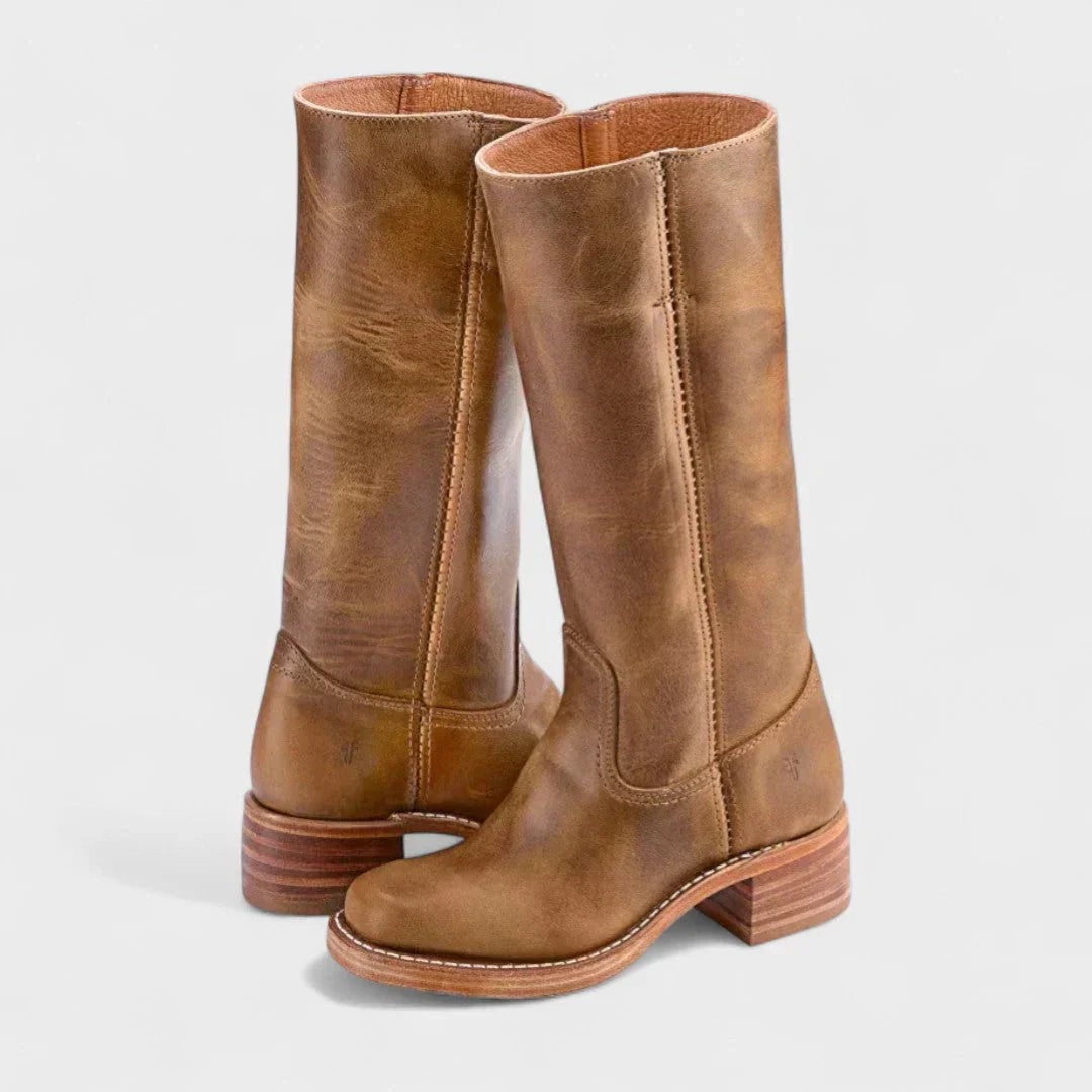 Tan knee-high boots shown from the front three-quarter view, highlighting the rounded toes, curved shaft panels, and layered heels.