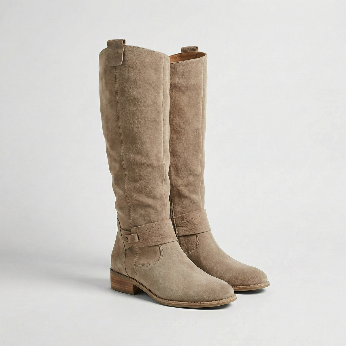 Taupe knee-high boots with softly gathered shafts, ankle buckle straps, rounded toes and low block heels, shown from the front three-quarter view.