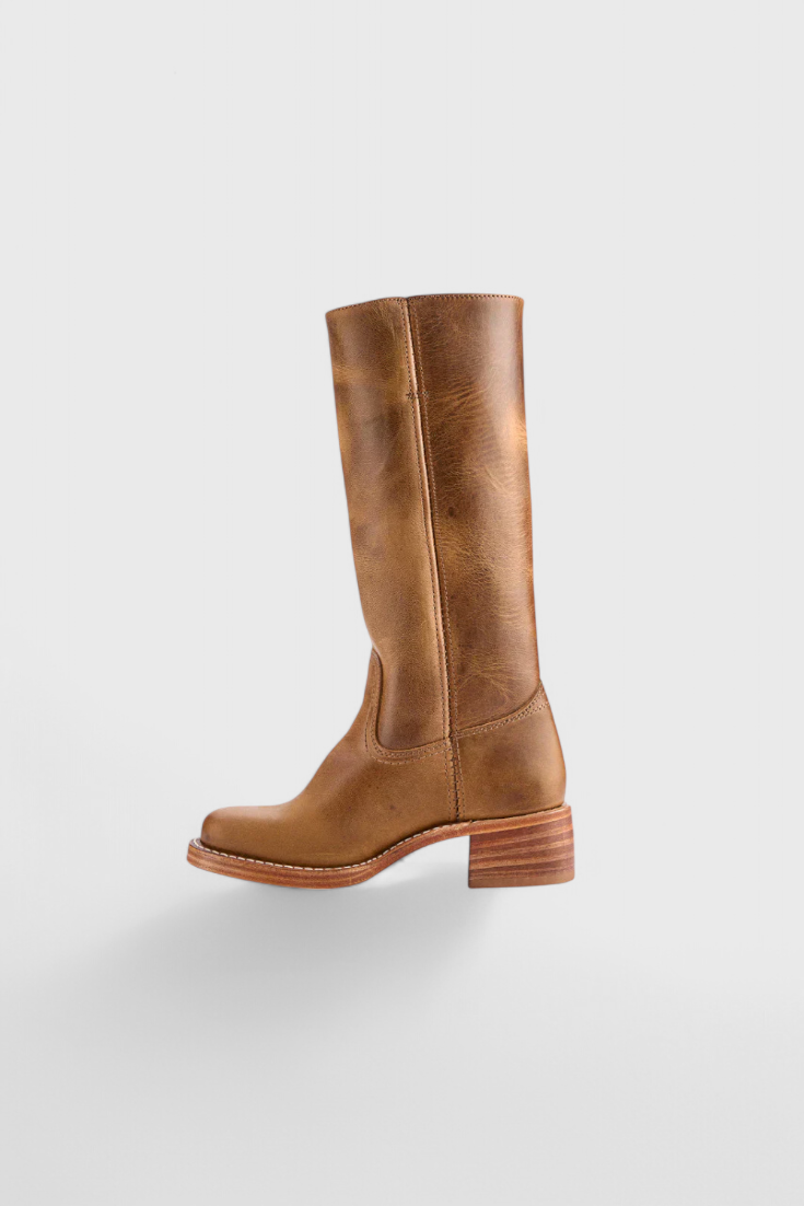 Warm brown knee-high boot shown at a distance in side profile, with a tall shaft, rounded toe, and low block heel.