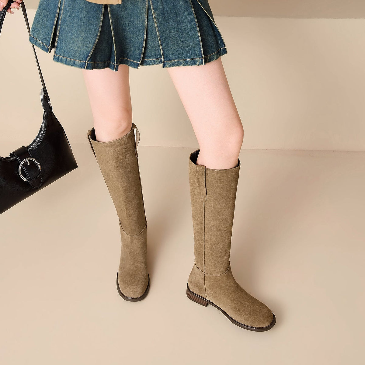 Front and angled view of tan knee-high boots paired with a denim skirt, highlighting the rounded toes and upper pull tabs.