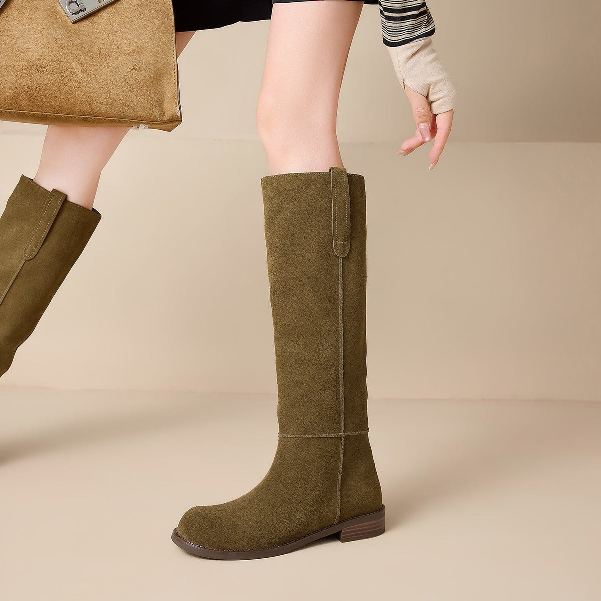 Single olive-tan knee-high boot in side profile, highlighting the straight shaft, decorative pull tab, vertical seam, and low heel.