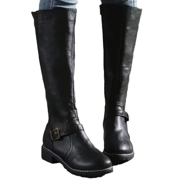 Black knee-high riding boots isolated against a white background, showing their tall silhouette, rounded toes, buckle strap, and sturdy soles.
