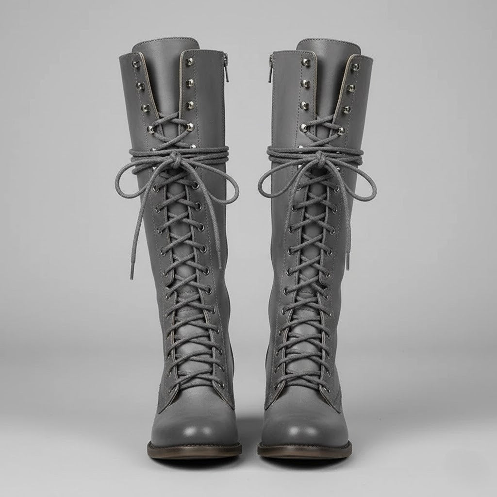 Front view of gray knee-high boots with long laces, metal eyelets, rounded toes, and block heels.