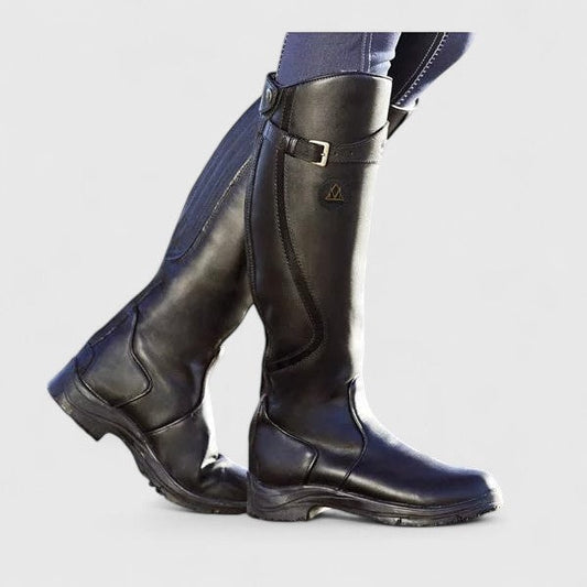 Black knee-high riding boots shown in a side view, with rounded toes, low block heels, adjustable shaft buckles, and textured outsoles.