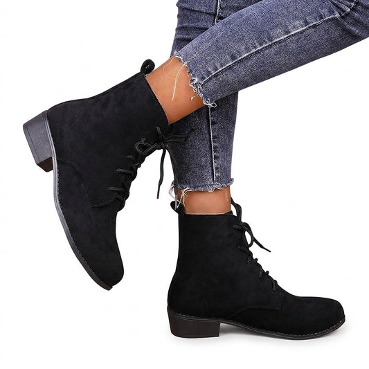Black lace-up ankle boots with rounded toes and low block heels shown worn with cropped jeans in a side view.