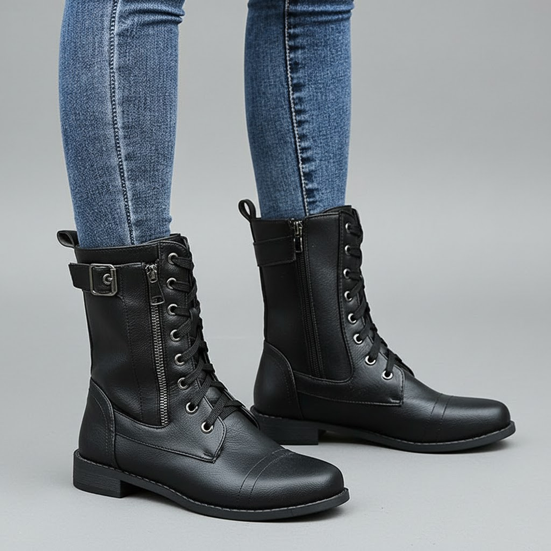 Black lace-up ankle boots worn with blue jeans, shown from an angled side view with visible side zips and low heels.