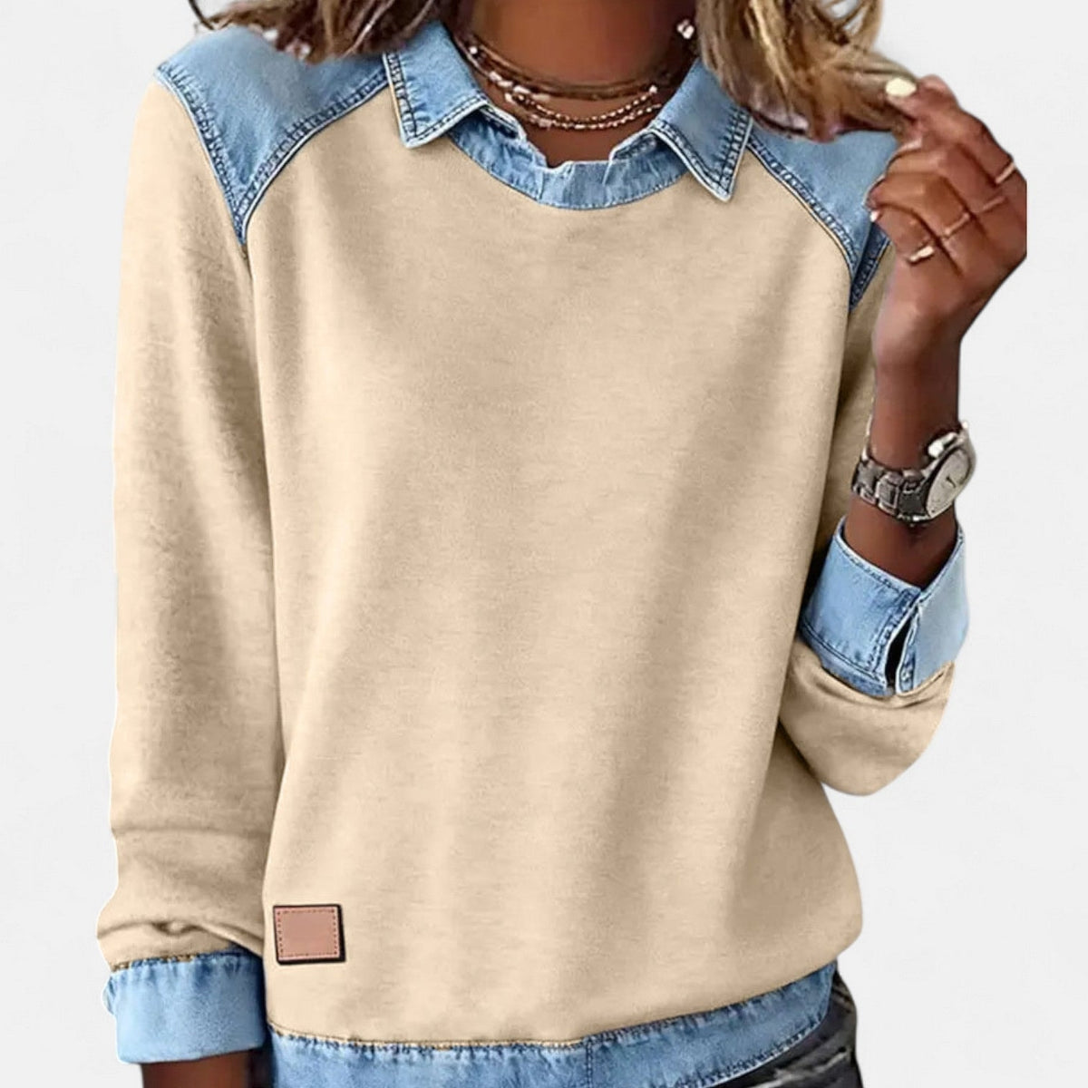 Front view of the beige-gold sweater with a blue pointed collar, shoulder panels, cuffs, and hem.