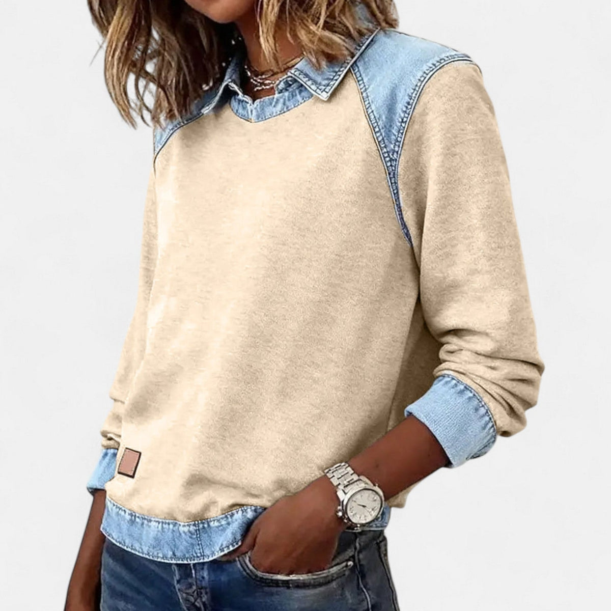 Three-quarter view of the beige-gold sweater paired with jeans, highlighting its relaxed silhouette and blue trim.