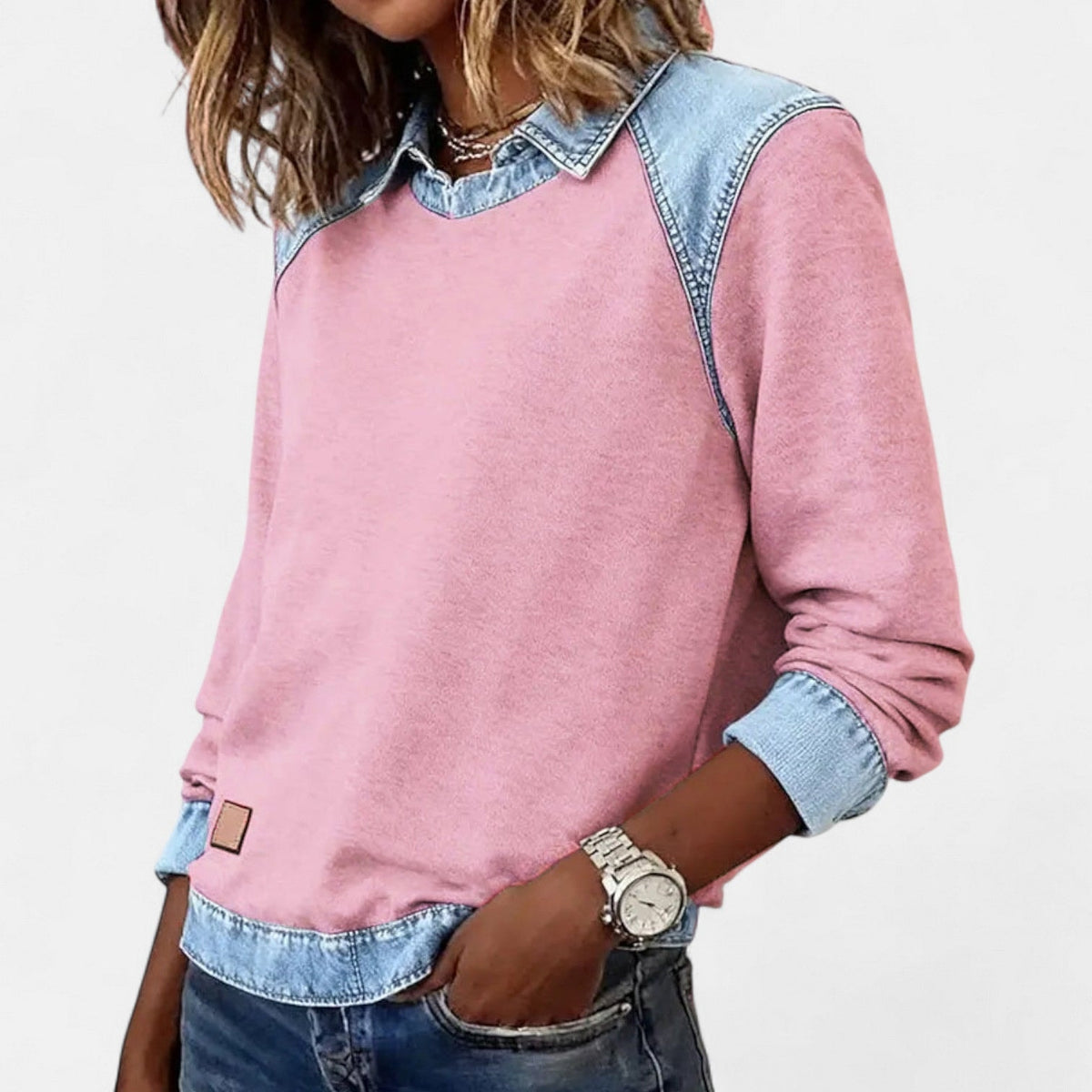 Three-quarter view of the pink long sleeve sweater with one hand in a pocket and the blue cuff turned up.