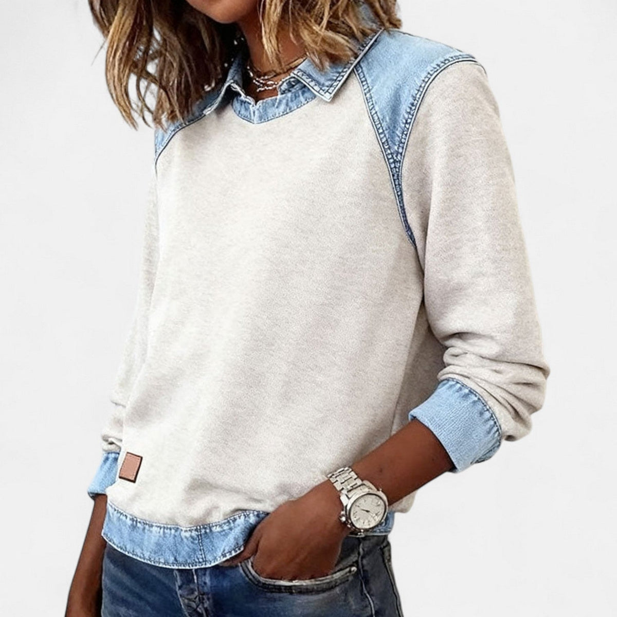 Three-quarter view of the beige layered-collar sweater showing its relaxed fit and contrasting cuff and hem details.