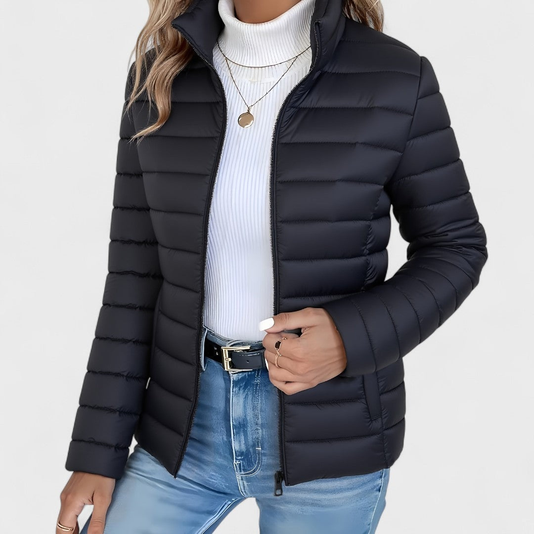 Dark navy quilted jacket shown zipped partway, highlighting the horizontal quilting and fitted hip-length shape.