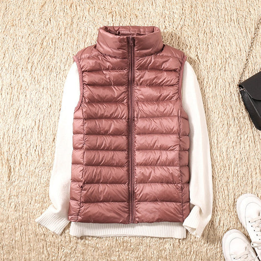 Mauve quilted zip-up puffer vest layered over a white sweater, viewed from above with its raised collar and side pockets visible.